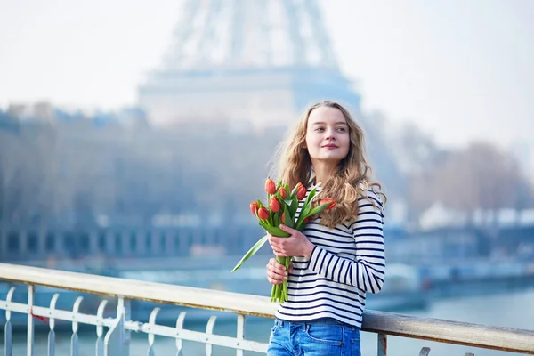 Menina com um monte de tulipas vermelhas perto da torre Eiffel — Fotografia de Stock