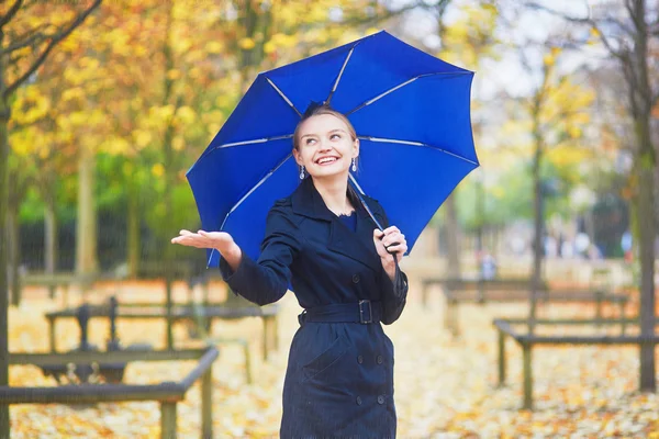 Giovane donna con ombrello blu nel giardino lussemburghese di Parigi in un giorno di pioggia autunnale o primaverile — Foto Stock