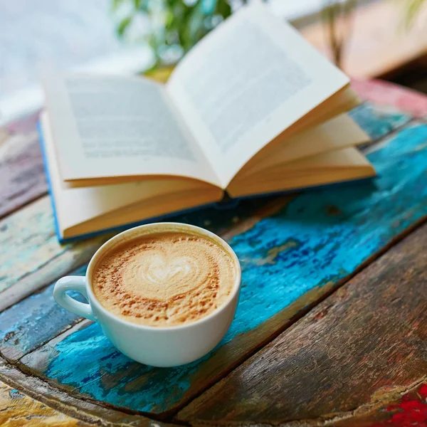 Kopje koffie en een boek over een houten tafel — Stockfoto