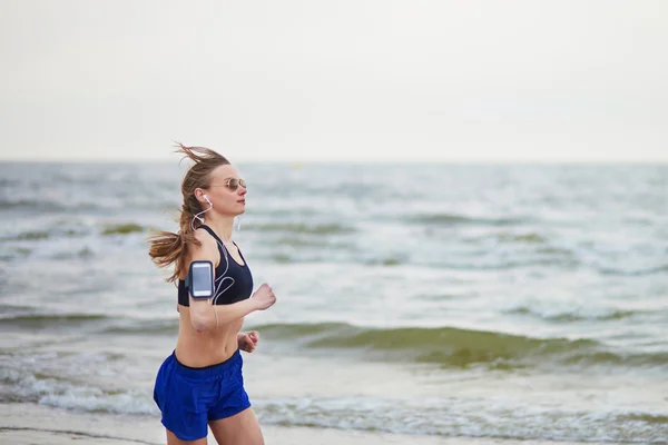 年轻的健身跑在海滩上慢跑的女人 — 图库照片