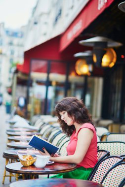Woman drinking coffee and reading a book in cafe
