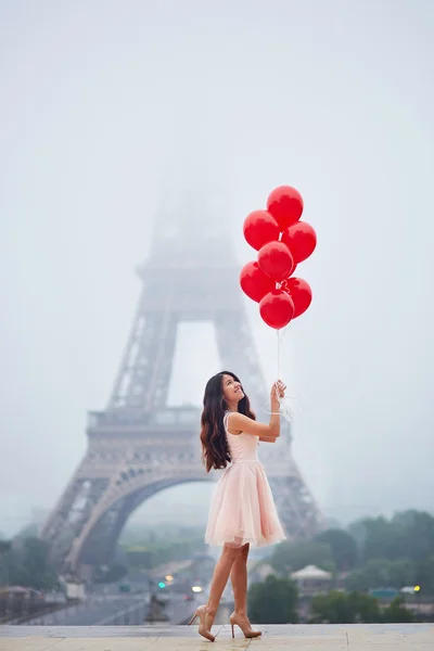 Mujer parisina con globos rojos frente a la torre Eiffel — Foto de Stock