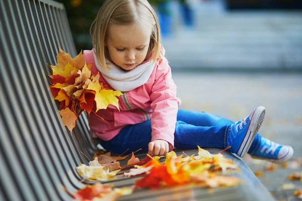 Menina Adorável Criança Sentar Banco Recolher Folhas Caídas Parque Outono — Fotografia de Stock