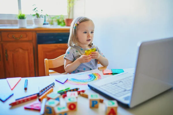 幼児の女の子は ラップトップの前で図形を学ぶ 子供はコンピュータを使って友人や幼稚園の生徒とコミュニケーションを取る 子供のための教育やオンライン通信 ホームエンターテイメントに滞在する — ストック写真