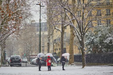 Paris 'teki Eyfel Kulesi' nin önünden geçen insanlar yoğun kar yağışı görüyorlar. Paris, Fransa 'da alışılmadık hava koşulları