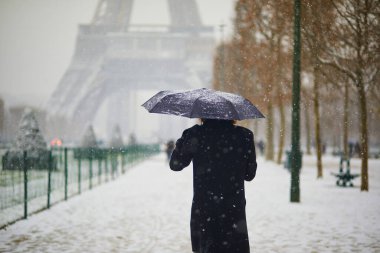 Paris 'teki Eyfel Kulesi' nin önünden geçen insanlar yoğun kar yağışı görüyorlar. Paris, Fransa 'da alışılmadık hava koşulları