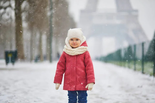 フランスで大雪の日にエッフェル塔の近くの愛らしい幼児の女の子 雪と遊ぶ幸せな子供 子供のための冬の活動 — ストック写真