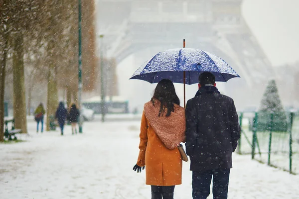 パリのエッフェル塔を雪の多い日に通過するカップル フランスで異常な天気予報 — ストック写真