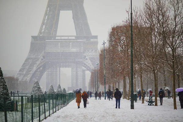 パリのエッフェル塔を大雪の日に通り過ぎる人々 フランスで異常な天気予報 — ストック写真