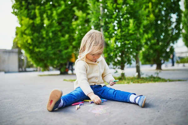 可爱的蹒跚学步的小女孩用彩色粉笔画沥青 幼儿户外活动及创意游戏 — 图库照片