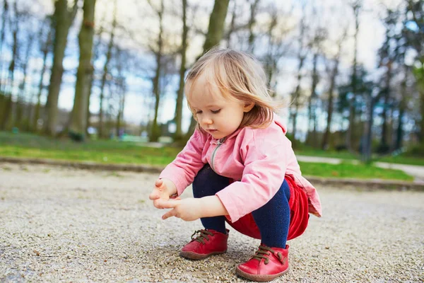 公園で愛らしい赤ちゃんの女の子は ハンカーに座って小さな石で遊んでいます 屋外で楽しんでいる小さな子供 — ストック写真