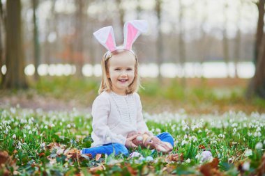Tavşan kulaklı bir kız Paskalya 'da yumurta avı oynuyor. Bir sürü kartopu çiçeğiyle çimenlerde oturan ve çikolatalı tavşan yiyen bir çocuk. Paskalyayı parkta ya da ormanda kutlayan küçük bir çocuk.