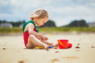 Brittany, Fransa 'nın Atlantik kıyısındaki kumsalda oynayan sevimli küçük kız. Küçük çocuk deniz ya da okyanus kenarında tatilin tadını çıkarıyor. Çocuklarla seyahat etmek.
