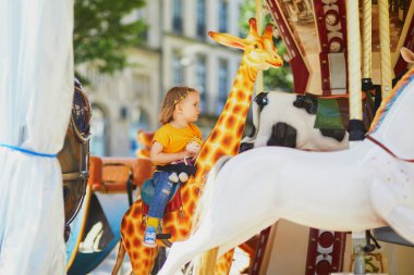 Çocuk, Quimper, Fransa 'da klasik Fransız atlıkarıncasında eğleniyor. Oyun bahçesindeki sevimli küçük kız. Küçük çocuklar için açık hava aktiviteleri
