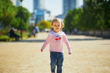 Fransa 'nın Paris caddesinde koşan neşeli küçük kız. Mutlu çocuk bir yaz günü dışarıda oynuyor. Çocuklar için açık hava aktivitesi