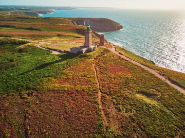 Cape Frehel 'in deniz feneriyle manzarası, Fransa' nın Brittany kentindeki en popüler turizm merkezlerinden biri. Ünlü GR34 izleme yolu boyunca yaygın olarak bilinen turist çekimini gösteren hava aracı görüntüsü
