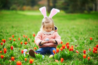 Paskalya 'da yumurta avında tavşan kulağı takan sevimli küçük bir kız. Bebek, gras 'da renkli yumurta arıyor. Paskalyayı ormanda kutlayan küçük bir çocuk. Soğuk hava ile erken Paskalya