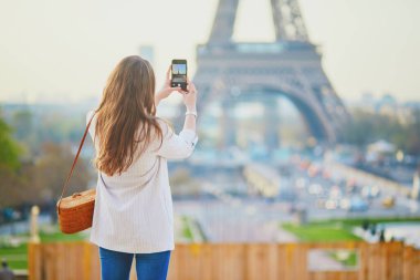 Paris, Fransa 'da Eyfel kulesinin akıllı telefonuyla fotoğraf çeken bir kız. Fransa 'da tatil yapan bir turist. Genç kadın video blogu kaydediyor