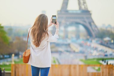 Paris, Fransa 'da Eyfel kulesinin akıllı telefonuyla fotoğraf çeken bir kız. Fransa 'da tatil yapan bir turist. Genç kadın video blogu kaydediyor