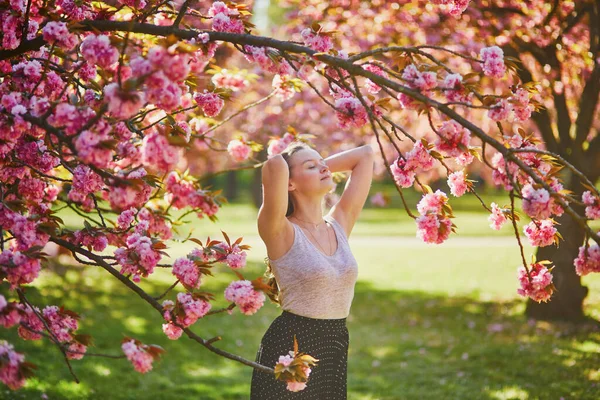 春の日に桜の庭で美しい女の子 フランス パリ近郊の有名なスコー公園の若い女性 — ストック写真