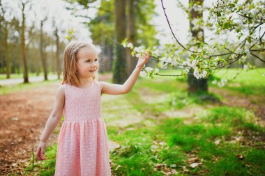 Fransa, Paris yakınlarındaki Sceaux Parkı 'nda güneşli bahar gününün tadını çıkaran pembe elbiseli sevimli üç yaşında bir kız.
