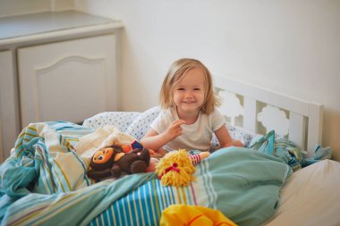 Uyandıktan hemen sonra pijamalı mutlu bir kız yatakta oturuyor. Küçük çocuklar için gündüz şekerlemeleri