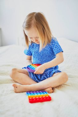 Sevimli küçük kız popo hareketleriyle oynuyor. Çocuk baloncuk esnek silikon duyusal oyuncaklarla oynuyor. Rahatlama ve stres önleyici oyuncaklar
