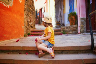 Fransa 'nın güzel Akdeniz kasabası Collioure' un caddesinde oturan sevimli üç yaşında bir kız. Çocuklarla seyahat etmek. Çocuklarla Tatil