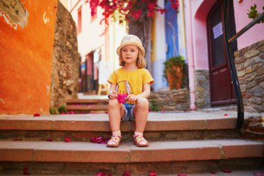 Fransa 'nın güzel Akdeniz kasabası Collioure' un caddesinde oturan sevimli üç yaşında bir kız. Çocuklarla seyahat etmek. Çocuklarla Tatil