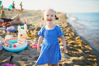 Mavi elbiseli mutlu küçük kız Fransa 'nın Akdeniz sahilinde eğleniyor. Neşeli çocuk denizde tatilin tadını çıkarıyor. Çocuklar için açık hava yaz etkinlikleri