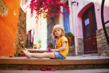 Fransa 'nın güzel Akdeniz kasabası Collioure' un caddesinde oturan sevimli üç yaşında bir kız. Çocuklarla seyahat etmek. Çocuklarla Tatil