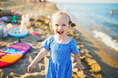 Mavi elbiseli mutlu küçük kız Fransa 'nın Akdeniz sahilinde eğleniyor. Neşeli çocuk denizde tatilin tadını çıkarıyor. Çocuklar için açık hava yaz etkinlikleri