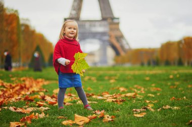 Kırmızı pançolu sevimli küçük kız bir sonbahar günü Eyfel kulesinde yürüyordu. Mutlu çocuk Paris, Fransa 'nın bir caddesinde eğleniyor. Çocuklar için açık hava sonbahar aktiviteleri