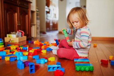 Anaokulunda ya da anaokulunda renkli plastik bloklarla oynayan sevimli küçük bir kız. Çocuklar için yaratıcı oyunlar