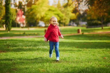 Sonbahar parkında oynayan sevimli küçük kız. Mutlu çocuk güz gününün tadını çıkarıyor. Çocuklar için açık hava etkinlikleri