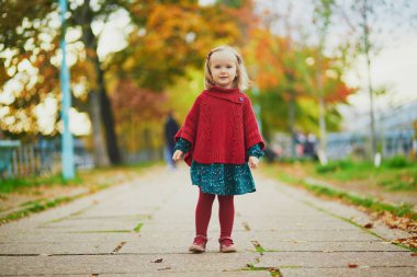 Fransa 'nın Paris kentinde, sonbahar parkında oynayan sevimli küçük kız. Mutlu çocuk güz gününün tadını çıkarıyor. Çocuklar için açık hava etkinlikleri