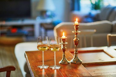 İki kadeh beyaz şarap ve iki mum güzel akşam ışığında.