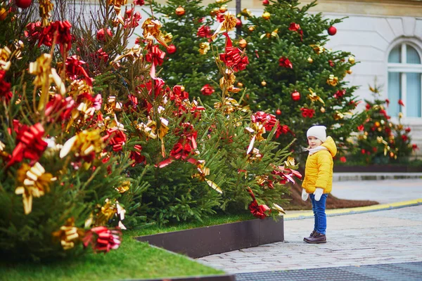 フランスで黄色と赤の弓で飾られたクリスマスツリーの近くの愛らしい未就学児の女の子 子供と一緒に季節の冬の休日を祝う — ストック写真