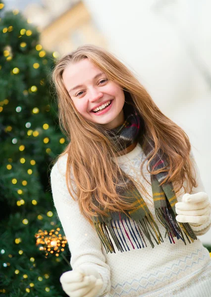 Girl with a sparkler near brightly Christmas tree — Stock Photo, Image
