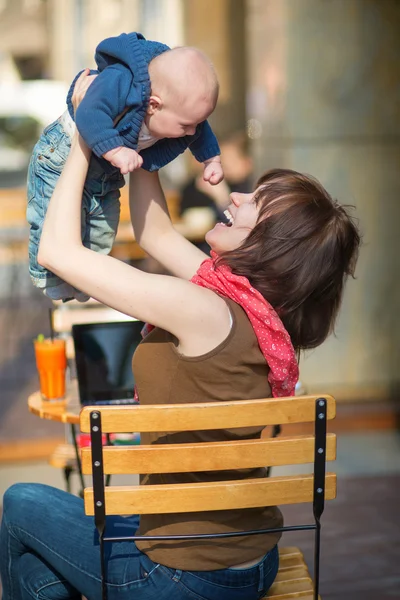 Felice giovane madre con suo figlio in un caffè di strada — Foto Stock