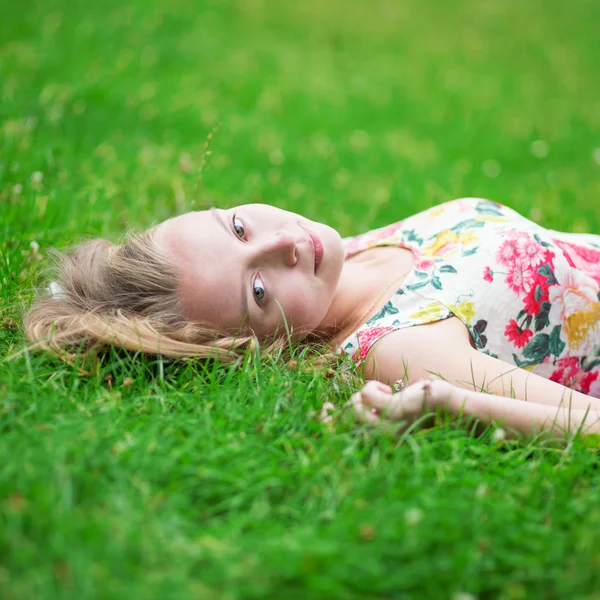 Krásná mladá dívka ležící na trávě — Stock fotografie