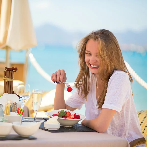Junge Frau isst Früchte in einem Strandrestaurant — Stockfoto