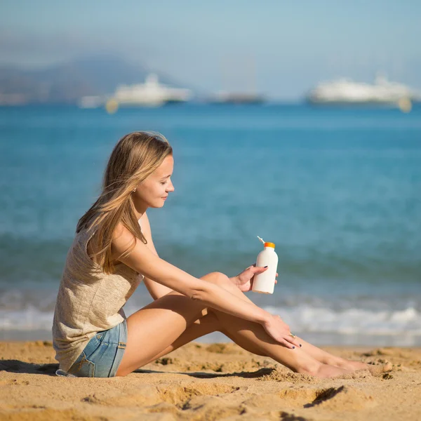 Young woman applying sunscreen on her legs — Stock Photo, Image