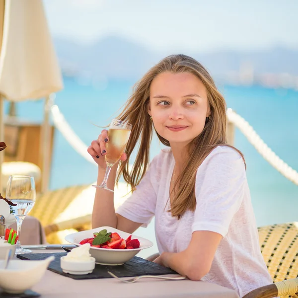 Młoda kobieta jedzenie owoców w restauracji na plaży — Zdjęcie stockowe