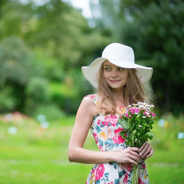 Young girl in white hat holding flowers — Stock Photo, Image