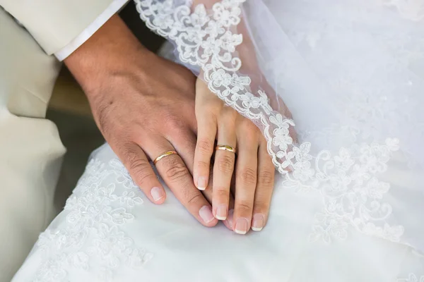 Manos con anillos contra vestido de novia — Foto de Stock