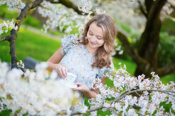 Beautiful girl drinking tea in garden — Stock Photo, Image