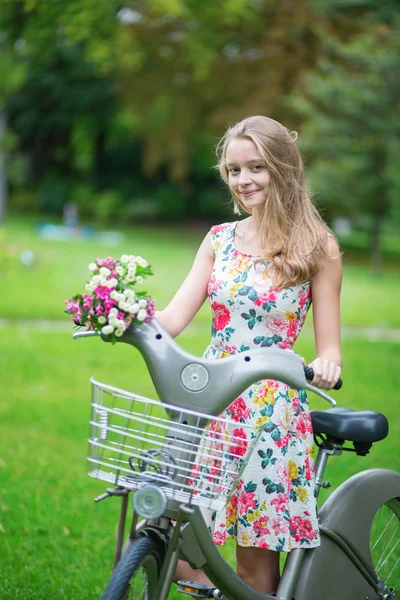 Chica con bicicleta y flores en el campo —  Fotos de Stock