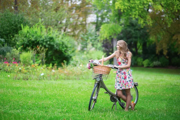 Ragazza con bicicletta e fiori in campagna — Foto Stock