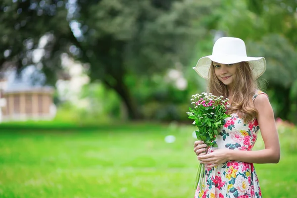 Chica en sombrero blanco sosteniendo ramo de flores —  Fotos de Stock